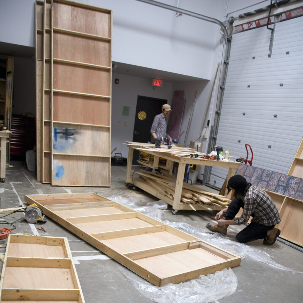 two men building set walls in a workshop