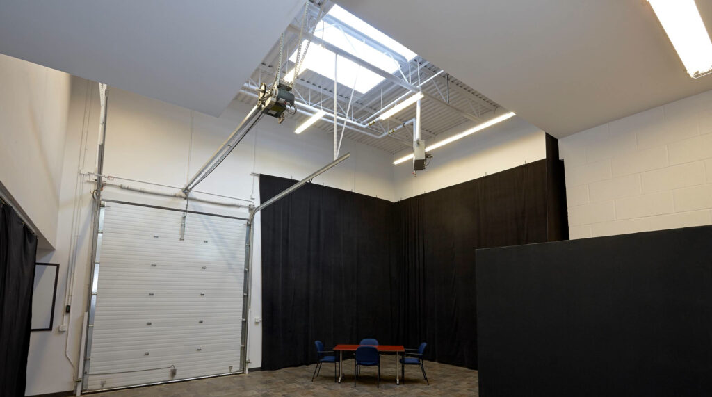 high ceiling room with large square skylight and garage door on back wall