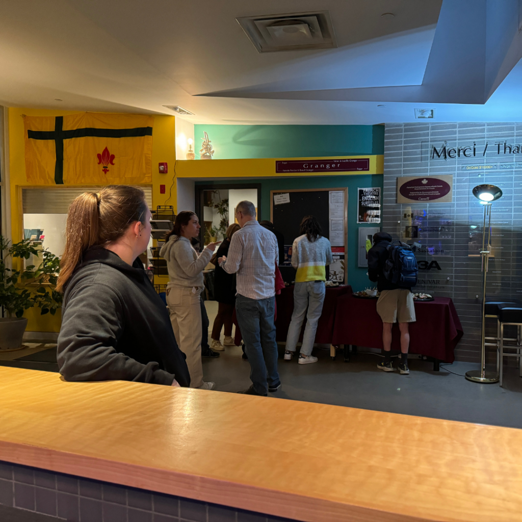 people standing in a lobby visiting and eating food