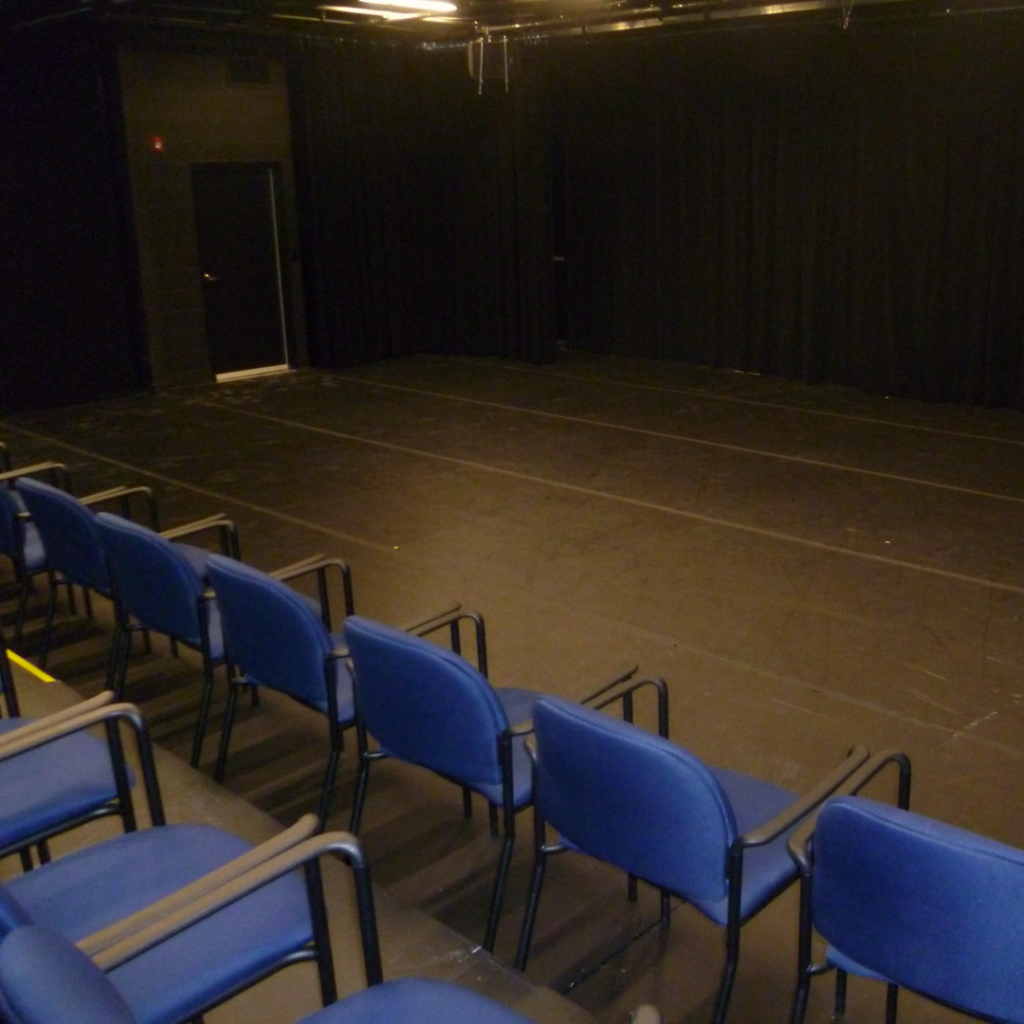 all black room with blue chairs on risers