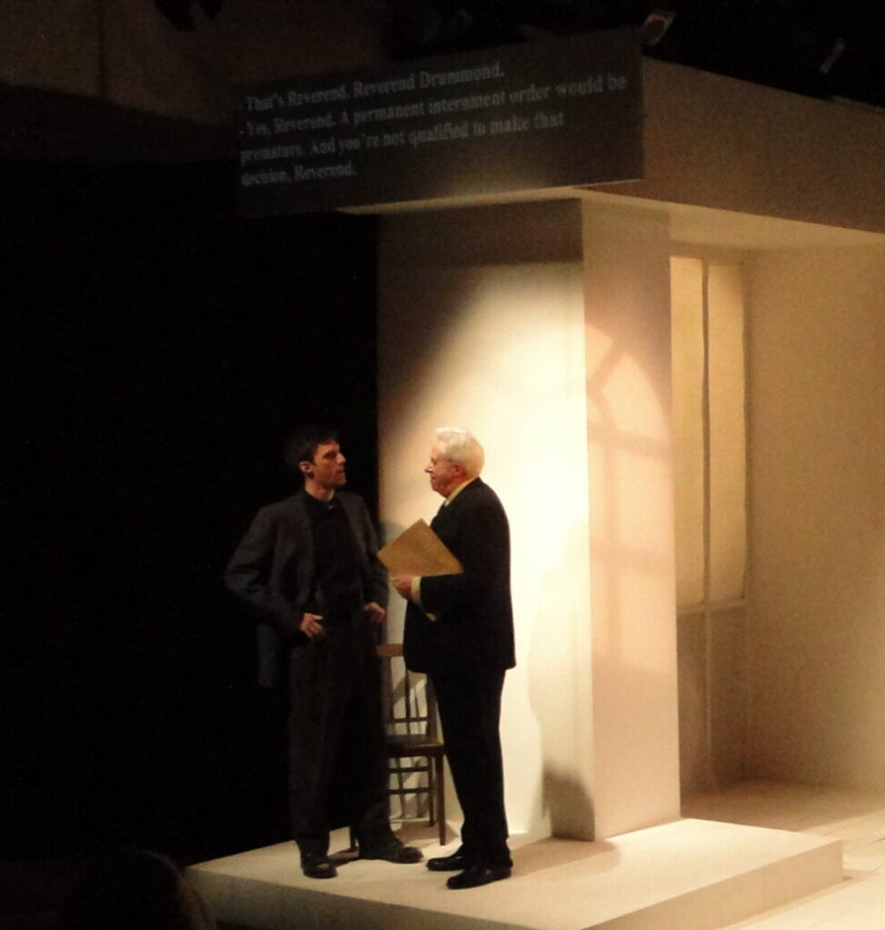 two men are talking to each other under a porch light on a theatre set