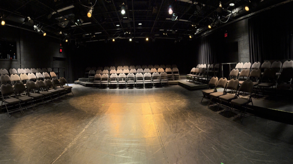 empty performance space with 3 rows of folding chairs along 3 walls in u shape